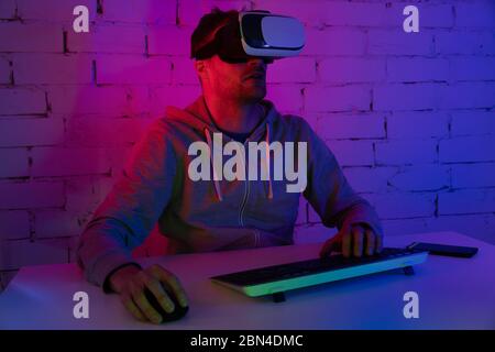 VR gaming - man playing video games with virtual reality headset in room with neon lighting Stock Photo