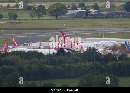 Glasgow, UK. 12th May, 2020. Pictured: Telephoto view of Glasgow Airport. Virgin Atlantic move more of their aircraft to Glasgow Airport for storage during the Coronavirus (COVID19) extended lockdown. Seen on the Tarmac are two Boeing 747-400 and two Airbus A330-300 Aircraft amongst4 the other number of ground aircraft from different airlines who face the same or similar fate at Virgin. Virgin Atlantic announced they will close down their Gatwick Operations indefinitely, which will have massive knock on effect for South East of the UK. Credit: Colin Fisher/Alamy Live News Stock Photo
