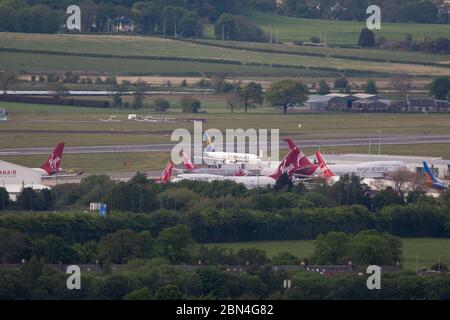 Glasgow, UK. 12th May, 2020. Pictured: Telephoto view of Glasgow Airport. Virgin Atlantic move more of their aircraft to Glasgow Airport for storage during the Coronavirus (COVID19) extended lockdown. Seen on the Tarmac are two Boeing 747-400 and two Airbus A330-300 Aircraft amongst4 the other number of ground aircraft from different airlines who face the same or similar fate at Virgin. Virgin Atlantic announced they will close down their Gatwick Operations indefinitely, which will have massive knock on effect for South East of the UK. Credit: Colin Fisher/Alamy Live News Stock Photo