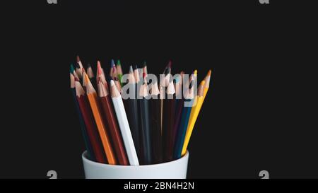 colored pencils in white cup on a black background Stock Photo