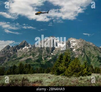 Rescue helicopter flying over the Grand Tetons, Jackson Hole, Wyoming, Yellowstone National Park. Stock Photo