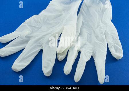 The photo shows white latex survey non-sterile powdered gloves on a blue background close up Stock Photo