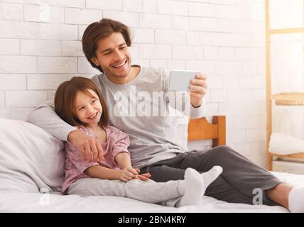 Happy family, little girl and dad taking selfie on smartphone Stock Photo
