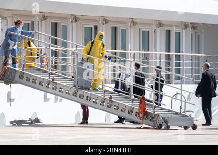 Montevideo, Uruguay. 12th May, 2020. The crew of the Australian cruise ship 'Greg Mortimer', which had numerous coronavirus-infected people on board, goes ashore in Montevideo in protective suits. The ship's crew was taken in buses to two hotels in the country's capital. The ship was anchored near Montevideo since the end of March. In April, more than 100 passengers were flown from the Uruguayan capital Montevideo to the Australian city of Melbourne. Credit: S. Mazzarovich/dpa/Alamy Live News Stock Photo