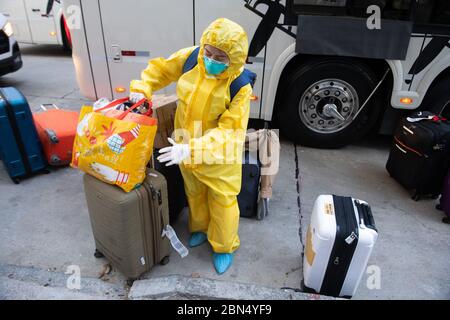 12 May 2020, Uruguay, Montevideo: A member of the crew of the Australian cruise ship 'Greg Mortimer', which had numerous coronavirus infected people on board, waves, carries suitcases and bags as it comes into the Regency Way Hotel. The 'Greg Mortimer' was anchored in Montevideo since the end of March. Now the crew was allowed to go ashore and was taken to two hotels. 35 crew members are said to have tested positive for Covid-19. Already in April more than 100 passengers had been flown from the Uruguayan capital to the Australian city of Melbourne. Photo: S. Mazzarovich/dpa Stock Photo