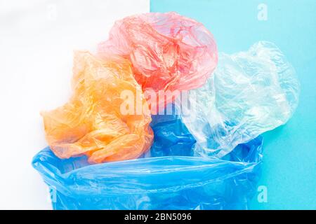 Flatlay colorful plastic bags in a garbage bag on a blue and white background. Sorting of polyethylene waste. Save the Earth concept. Environmental Stock Photo