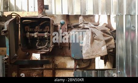 Old dismantled and rusty electric shield in an abandoned factory against the background of chaos Stock Photo