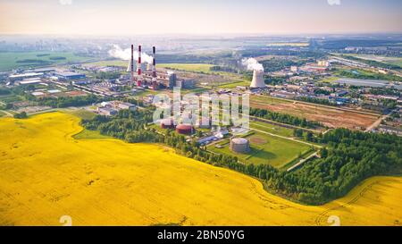 Panoramic aerial view of Belarus power plant with golden flowering field of rapeseed, canola or colza - two possibility for production of electric ene Stock Photo