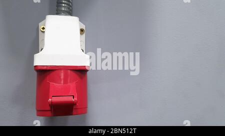 Three-phase 380 V high-voltage plug on a gray wall in a room with copy space Stock Photo