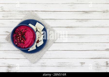 hummus consisting of beets, chickpeas in bowls. on a white wooden background, with bread chips. copy space. flat lay Stock Photo