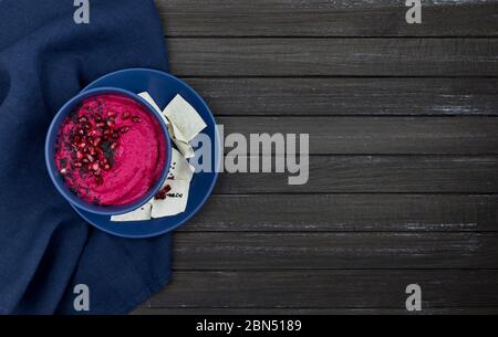 hummus consisting of beets, chickpeas in bowls. on a dark wooden background, with bread chips. copy space. flat lay Stock Photo