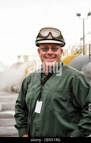 A worker in front of railroad tank cars at an industrial manufacturing facility. Stock Photo