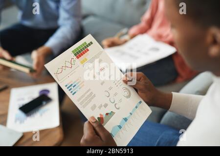High angle view of unrecognizable businessman holding statistics report while working on startup project with team in office, copy space Stock Photo