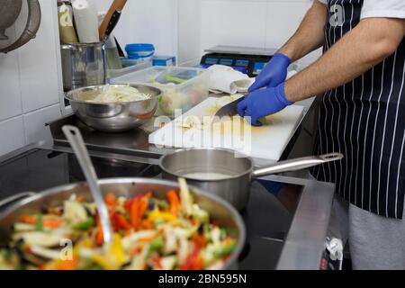 Unrecognizable man slicing apples while cooking fresh vegetables Stock Photo