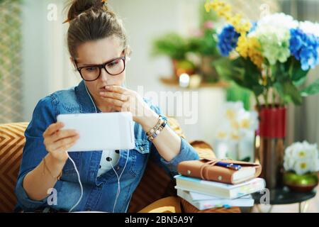 stylish housewife in jeans shirt with white headphones and tablet PC study online in the modern house in sunny day. Stock Photo