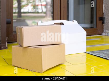 Delivery boxes on doorstep at home. Contactless food delivery. Safe shopping E-commerce purchase parcels at home. Boxes delivered to front door by Stock Photo