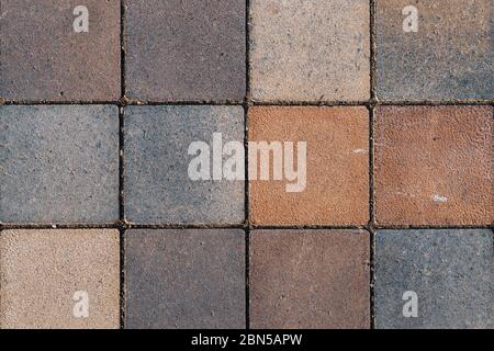 Weathered surface of rustic floor covered with square terracotta tiles of various shades of brown and gray colors Stock Photo