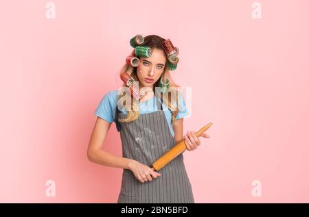 Strict housewife in apron with spots of flour and rolling pin in hands Stock Photo