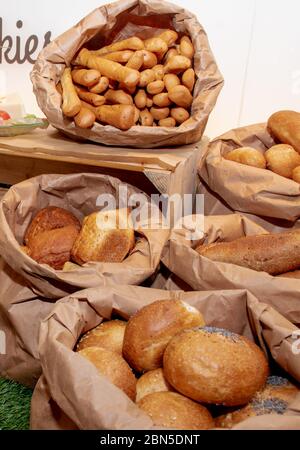 Selection of Fresh baked bread baskets and paper bags with bread roasted in the oven, croissants, baguettes, whole integral bread and pastry, rustic w Stock Photo