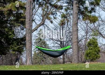 St. Paul, Minnesota.  Como Park. A man practicing social distancing by isolating himself in a hammock on a beautiful day in the park. Stock Photo