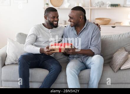 Happy Father's Day. Adult Black Son Congratulating His Senior Dad, Giving Gift Stock Photo