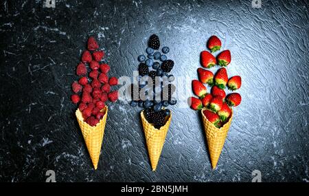 Summer berries in ice cream cones creative flatlay top view. Dark moody creative composition. Stock Photo