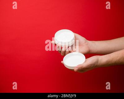 Male hand holding unbranded plastic tubewith white cream. Flacon for cream, toiletry. Bottle for professional cosmetics product. Skincare and beauty Stock Photo
