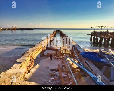 Abandoned old jetty at the beach in Hua Hin, Thailand. A lonely dog there is searching for food. Stock Photo