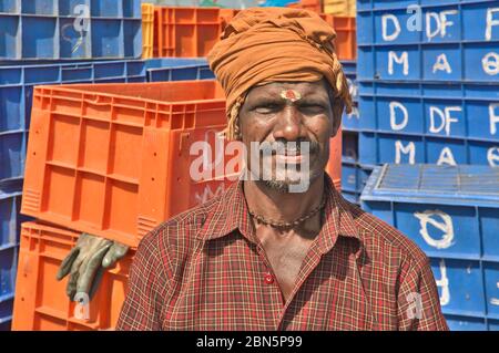Portrait of a Hindu fisherman in the Old Port in Mangalore (Mangaluru), Karnataka, India, with blue and orange plastic crates in the background Stock Photo