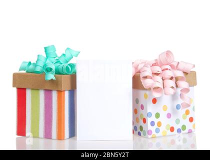 Two colorful festive present boxes with curly bows in pastel pink and turquoise with a blank card for copy space in between. Isolated on white. Stock Photo