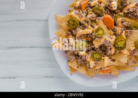 nacho chips corn garnished with ground beef, melted cheese, chili peppers in plate on wooden table mexican spicy food in mexico Stock Photo