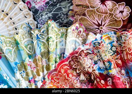 Flamenco hand fans with colorful floral pattern bunched together for abstract background. Spanish or Chinese influence Stock Photo