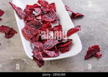 Diet healthy eating concept. Dried beet chips or baked beets in a white rectangular plate, on a gray concrete background. Organic natural food. Copy s Stock Photo