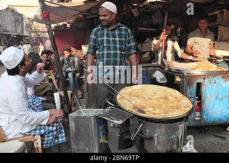 At a simple eatery in Thieves' Market (Chor Bazar), Bhendi Bazar, Mumbai, India, a giant roti (flatbread) is in the making on a tawa (hot iron plate) Stock Photo