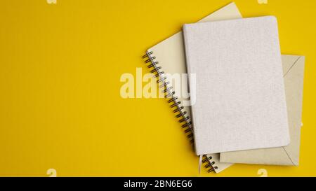 Pile of paper notebooks on yellow background. Flat lay, top view school of office supplies. Stock Photo
