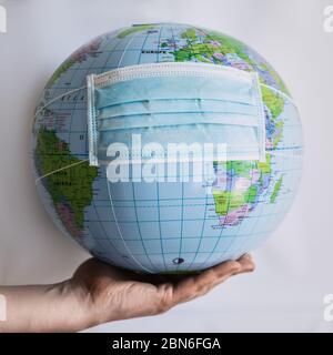Globe on hand with respiratory mask - Covid 19 Stock Photo