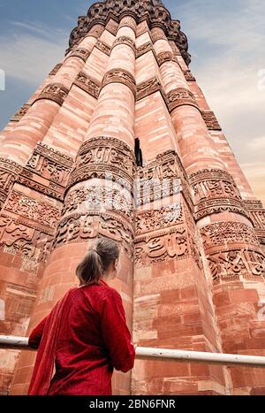 Woman in red costume is looking at Qutub Minar tower in Delhi, India Stock Photo