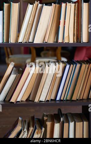 piles of books on a wooden bookshelf. Stock Photo
