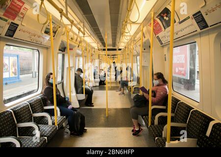 WIMBLEDON LONDON, 13 May 2020. UK.  Commuters in an  almost empty London underground train carriage  on the district line during what would normally be considered peak rush hour at 8 am. The government has announced a series of measures to slowly ease lockdown, which was introduced to fight the spread of the COVID-19 strain of coronavirus. Credit: amer ghazzal/Alamy Live News Stock Photo