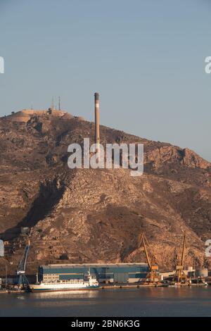 Boat docked in the port of Cartagena, (Murcia, España), with a mountain in the background and a large chimney Stock Photo