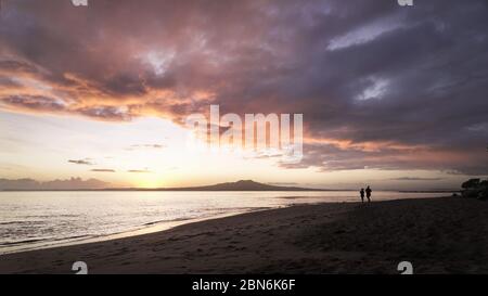 Silhouette man and woman running on the Milford beach at dawn Stock Photo