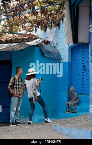 Chefchaouen, Morocco - October 15, 2017: Asian tourists visiting the picturesque village of Chefchaouen, taking photos in the medina Stock Photo