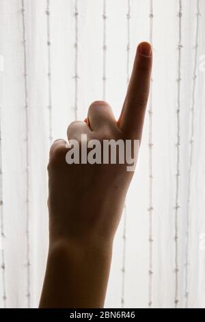 girl hand that with the index finger points upwards with a white curtain as a background Stock Photo