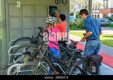 Good-humoured family uses an exemplary bicycle parking concept for a city stroll on foot Stock Photo