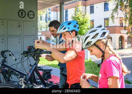 Good-humoured family uses an exemplary bicycle parking concept for a city stroll on foot Stock Photo