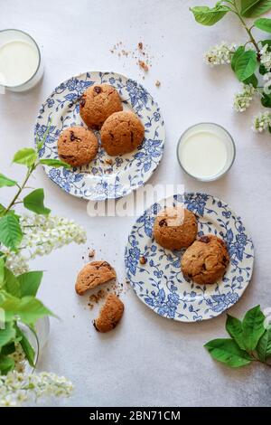 Flat lay shot of chocolate chip cookies with milk and some green blooming branches Stock Photo