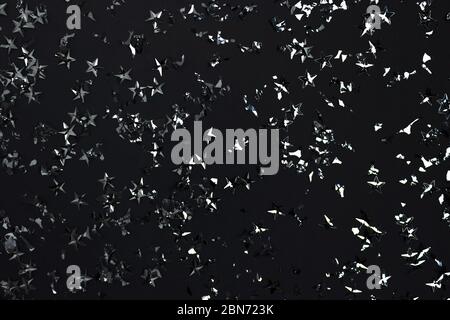 Silver stars confetti texture on a black background. Festive backdrop. Stock Photo