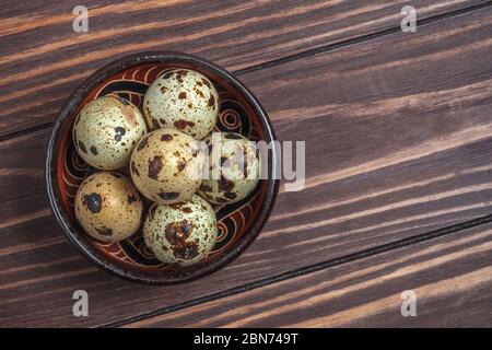 Quail eggs in a clay plate on a dark wooden background Stock Photo