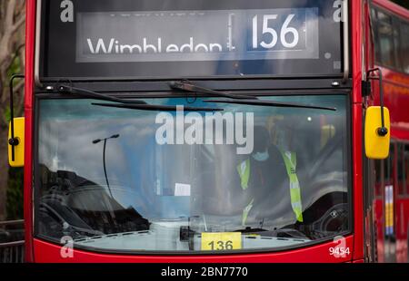 Wimbledon, London, UK. 13 May 2020. On day 51 of Coronavirus lockdown in the UK some businesses reopen and workers who cannot work from home are encouraged to travel to work by bike or walking if possible. Bus driver wearing a face mask at Wimbledon bus station. Credit: Malcolm Park/Alamy Live News. Stock Photo