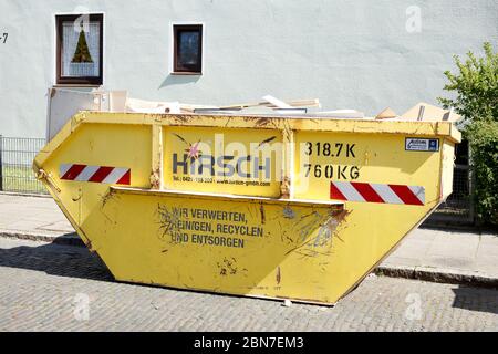 Yellow skip for building rubble standing on the street in front of a residential building, Germany, Europe Stock Photo